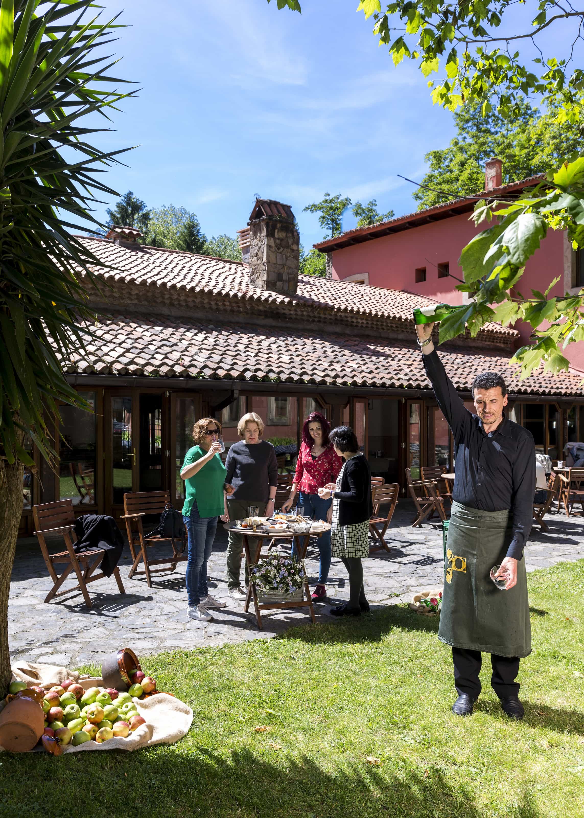 Camarero escanciado sidra para clientes en la terraza del Restaurante Llar de Molín del Parador de Gijón