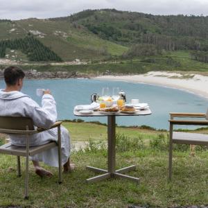 Un hombre desayuna en albornoz en la terraza de una habitación estándar de matrimonio del Parador de Muxía